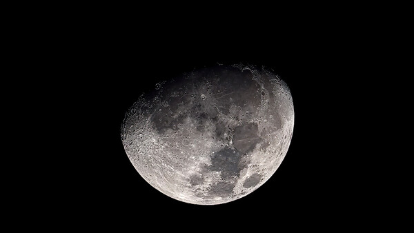 Waxing gibbous moon showing detailed surface features against black sky.