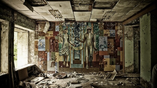 Abandoned interior room with deteriorating murals on walls and ceiling amid scattered debris and rubble.