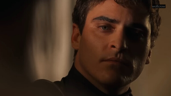 Man in dark clothing with dramatic side lighting against a blurred background.