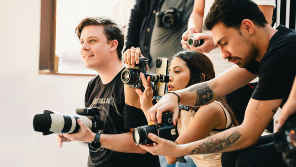 Photography workshop participants holding professional cameras and lenses during a hands-on training session.