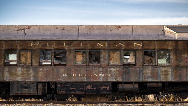 Weathered Pullman passenger train car with corroded metal exterior and broken windows.