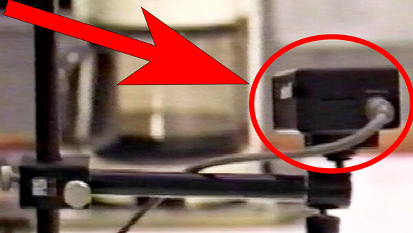 3D printer with red arrow indicating the extruder nozzle and circled detail of the printing head assembly.