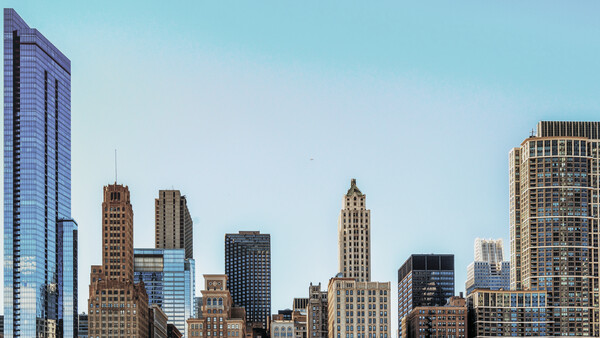 Downtown skyline with mix of historic and modern skyscrapers against clear blue sky.