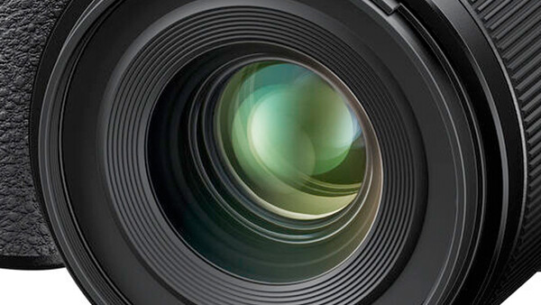 Close-up of a camera lens front element with multi-coated glass and internal lens groups visible.