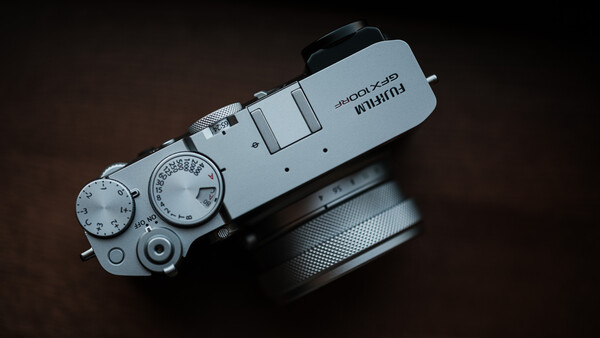 Top-down view of a silver rangefinder camera with manual dials and a black lens attached.
