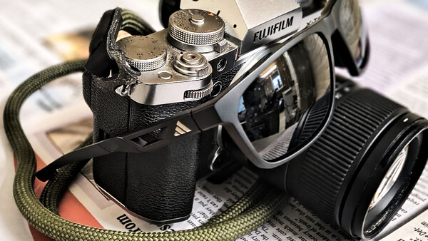 Vintage rangefinder camera with interchangeable lens on printed newspaper surface.