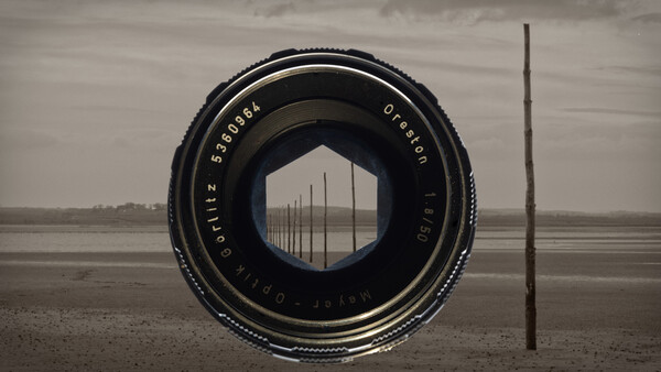 Vintage camera lens framing a row of utility poles stretching across a flat, desolate landscape under overcast sky.
