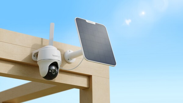 Solar-powered wireless security camera mounted on wooden beam with dual antenna and attached solar panel against blue sky.