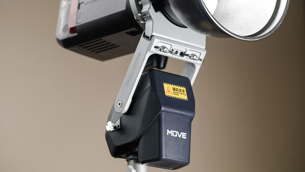 Flash unit with white bracket mounted on light stand against neutral background.