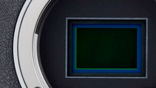 Camera sensor with blue and green color filter array pattern visible through open aperture.
