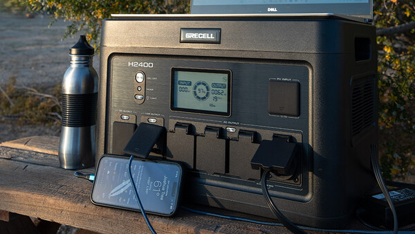 Duracell H2400 portable power station with attached solar panel and charging cable on outdoor wooden surface.