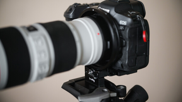 Canon EOS R5 mirrorless camera mounted on tripod with white telephoto lens attached.