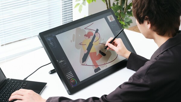 Designer using a stylus on a digital drawing tablet displaying abstract graphic artwork in progress.