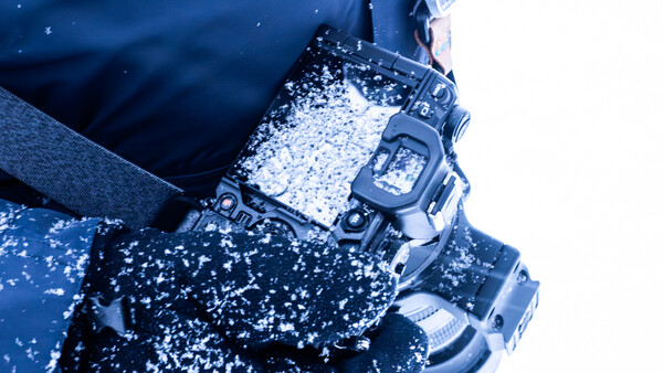 Digital watch covered in snow and ice against a blue winter background.