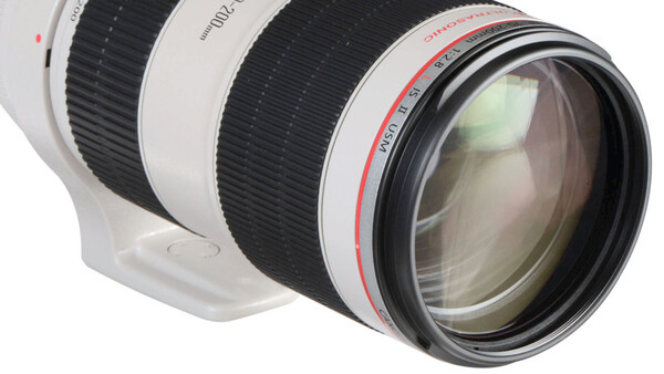 White telephoto lens with black focus ring and red text markings on barrel against white background.
