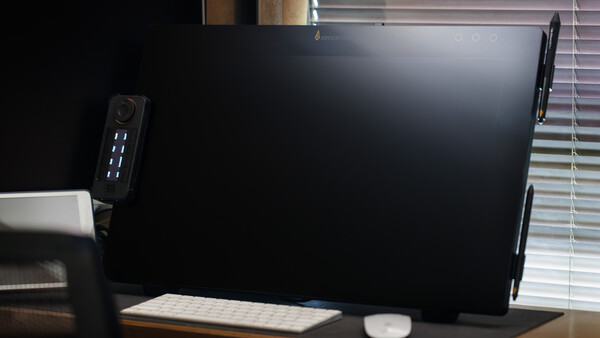 Desktop workspace with a large monitor, compact tower PC with illuminated ports, wireless keyboard, and mouse on a wooden desk.