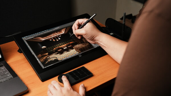 Digital artist using stylus on tablet displaying warm-toned landscape image with golden lighting.