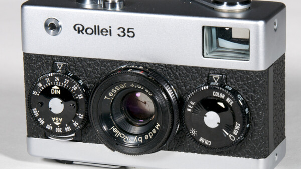 Rollei 35 compact film camera with white and black body, showing dual control dials and Tessar lens.