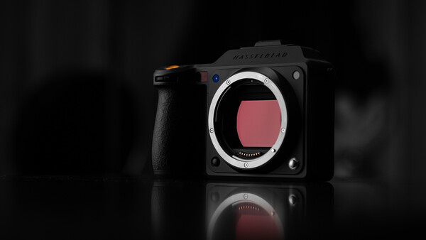 Mirrorless camera body with open sensor bay displayed against dark background with reflection.