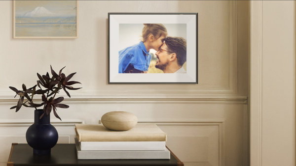 Framed portrait photograph displayed above a console table with books and a decorative vase.
