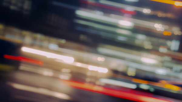 Motion-blurred light trails in horizontal streaks of red, white, green, and yellow against a dark background.