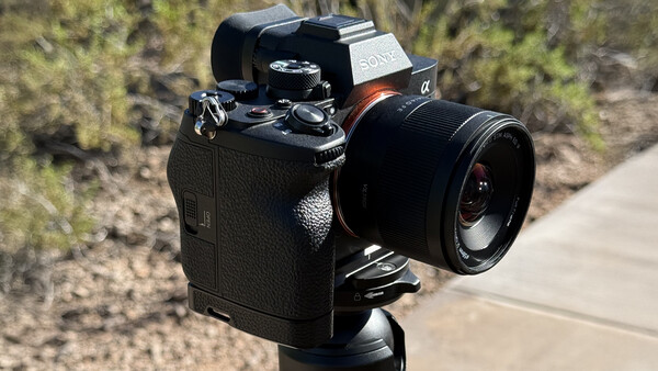 Sony mirrorless camera with prime lens mounted on tripod in outdoor setting.