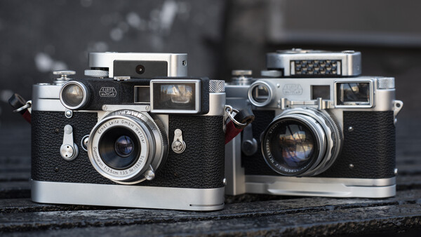 Two vintage rangefinder cameras with black leather bodies and chrome accents displayed side by side.