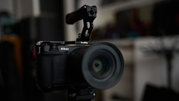 Nikon mirrorless camera with SmallRig rig mounted on top, featuring a microphone attachment and wireless receiver.