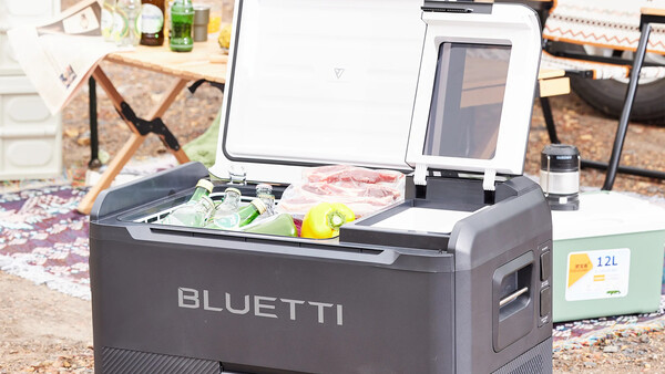 Bluetti portable power station with open lid displaying control panel and battery display outdoors.