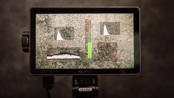 Viltrox monitor displaying waveform and focus peaking tools with live video feed on textured surface.