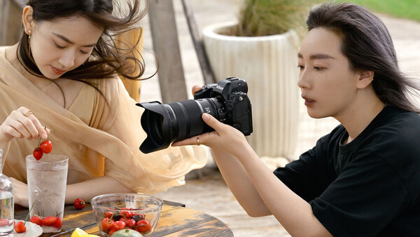 Food photographer captures a styled arrangement of fresh produce and strawberries using a professional DSLR camera.
