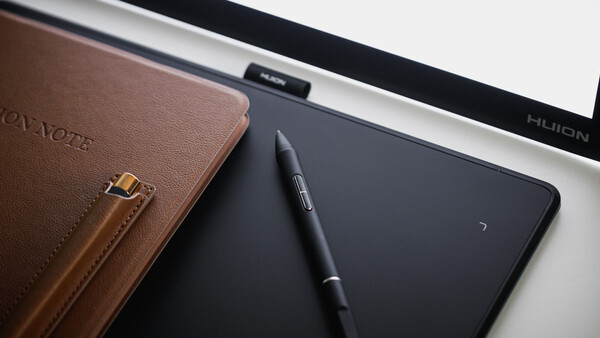 Brown leather notebook with stylus pen and digital tablet on white desk surface.