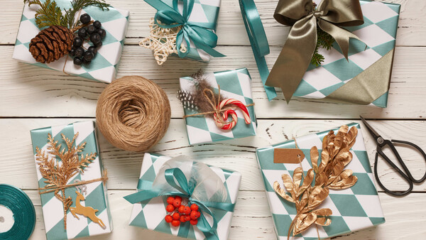 Flat lay of wrapped gifts with turquoise and gold accents arranged on white wooden surface.