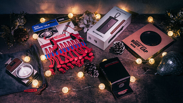 Flat lay of photography and beauty products arranged with warm string lights and decorative pinecones.