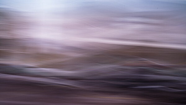 Blurred landscape with horizontal motion blur across layered terrain in purple and brown tones.
