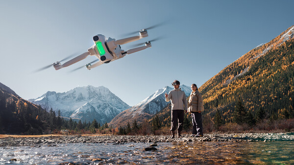 Drone flying over two people standing in a mountain valley stream.