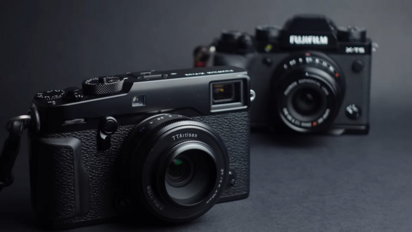 Three rangefinder-style digital cameras arranged on a gray surface with selective focus on the foreground model.