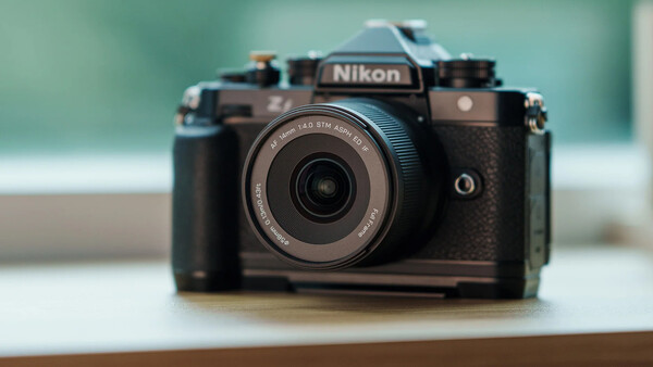 Nikon Z fc mirrorless camera with retro styling and compact prime lens on wooden surface.