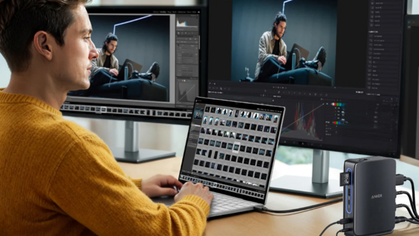 Video editor working at dual monitors with control panel and editing software open.