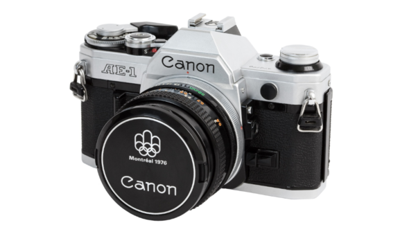 Canon AE-1 35mm SLR camera with silver top plate and black body, shown with standard lens and lens cap.