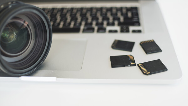 Camera lens and memory cards arranged on a laptop keyboard.