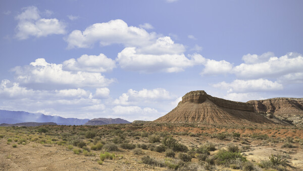 Distinctive cone-shaped butte rising from arid desert landscape under partly cloudy sky.
