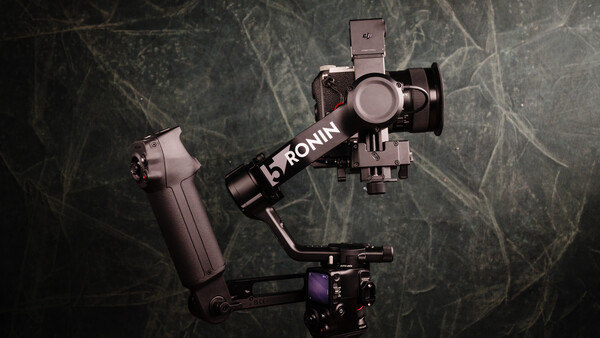 DJI Ronin gimbal with mounted smartphone stabilizer on textured dark background.