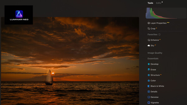 Sailboat silhouetted against dramatic golden sunset over calm ocean water.
