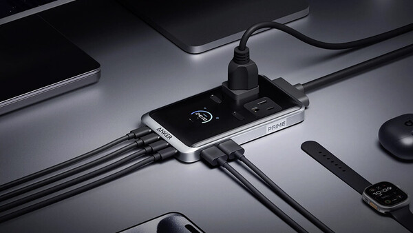 Smartphone with USB charging hub connected to multiple cables on minimalist desktop