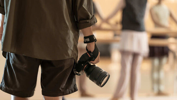 Photographer holding a DSLR camera with telephoto lens at a professional event