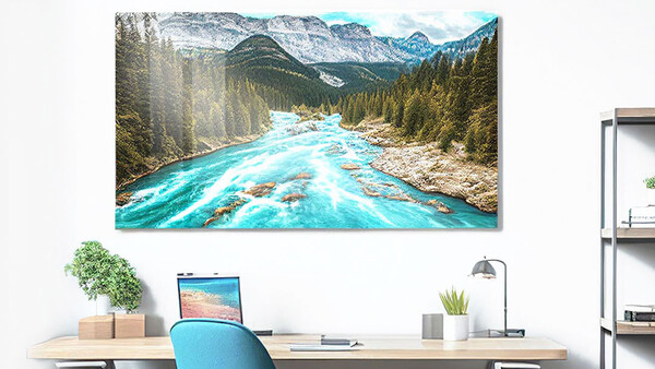 Turquoise river flowing through forested valley with snow-capped mountains in background.