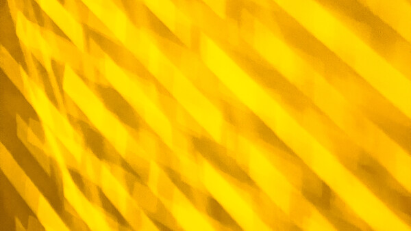 Abstract yellow diagonal lines creating a textured pattern with shadow and light variation