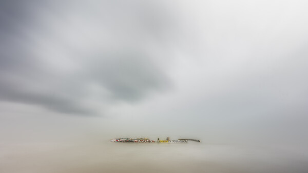 Minimalist landscape with industrial structure barely visible through dense fog and mist