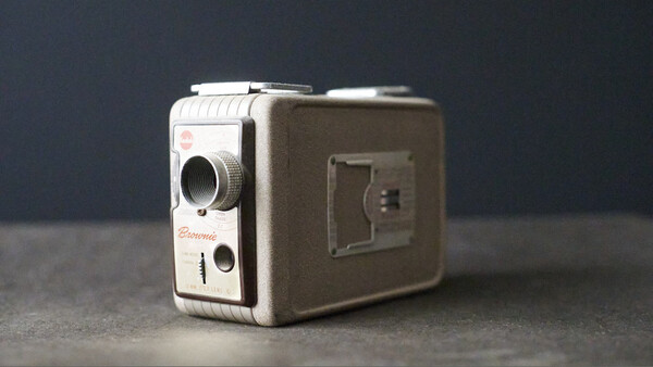 Vintage 8mm film camera with cream and brown two-tone body displayed against dark gray background